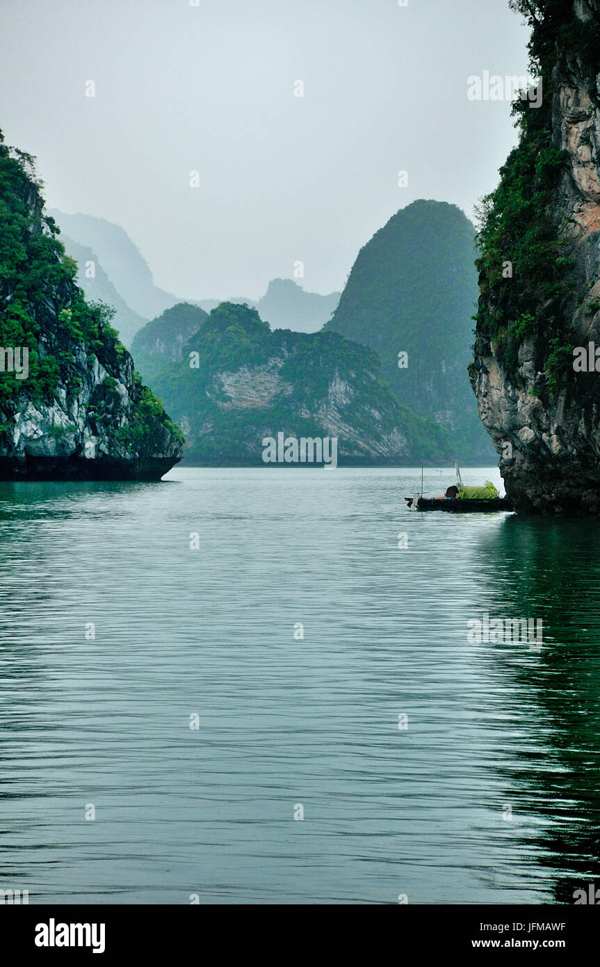 Vietnam, la bahía de Ha Long, vista a las montañas características de la Bahía de Halong, con una pequeña embarcación típica Foto de stock
