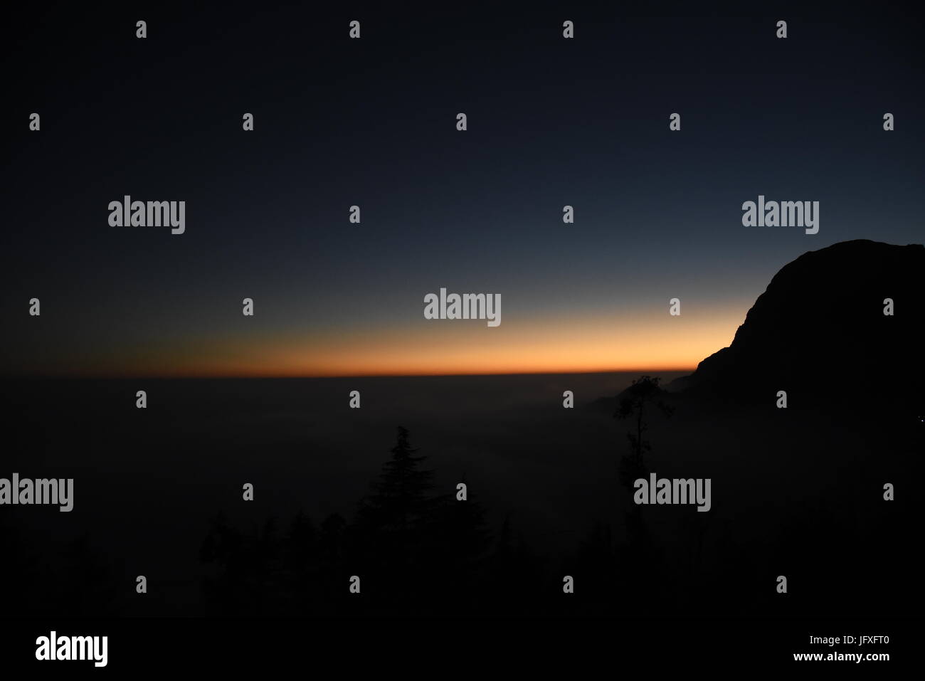 Scenic hermosa puesta de sol vista desde el punto más alto de la montaña naranja azul cielo en la oscuridad a Dhanaulti, Uttrakhand, India, Asia Foto de stock