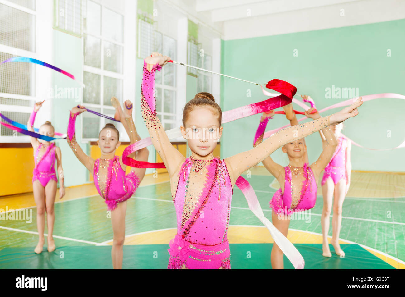 Un grupo de niñas preadolescentes vistiendo leotards espumoso rosado,  haciendo gimnasia rítmica con cinta de arte en la escuela sala de deportes  Fotografía de stock - Alamy
