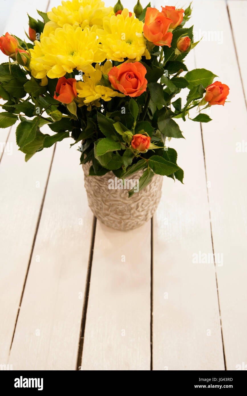 Jarrón de flores blancas sobre una mesa de estilo rústico. Vista desde  arriba. Florero rústico con rosas de color naranja y amarillo de los  crisantemos. Fondo blanco, lugar vacío, espacio de copia