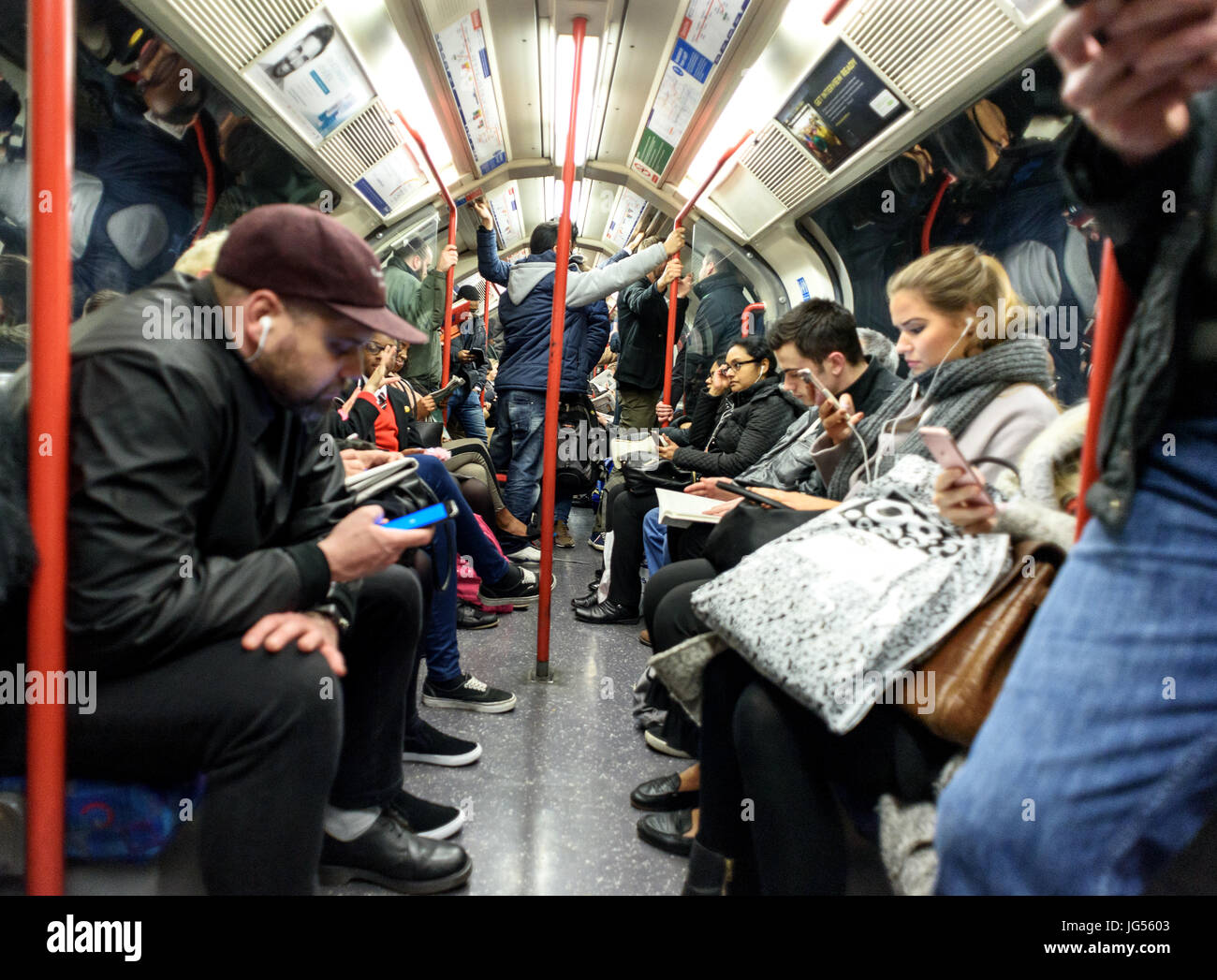 Diversos grupos mezclados cabalgando sobre un tren de Metro de Londres en sus vagones tanto sentado y de pie Foto de stock