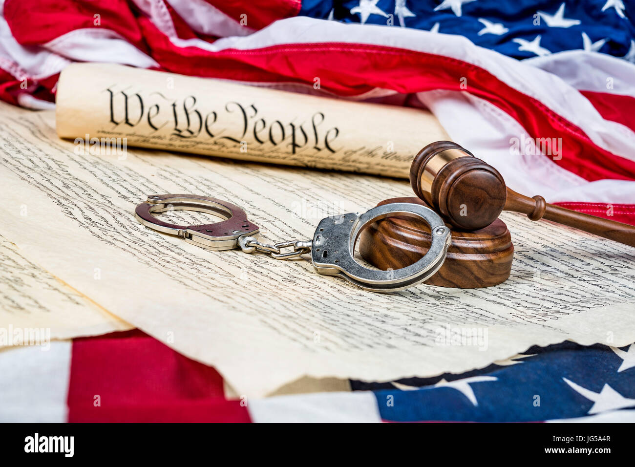 La Constitución de los Estados Unidos acumulan en una bandera americana con un martillo y esposas en primer plano. Foto de stock
