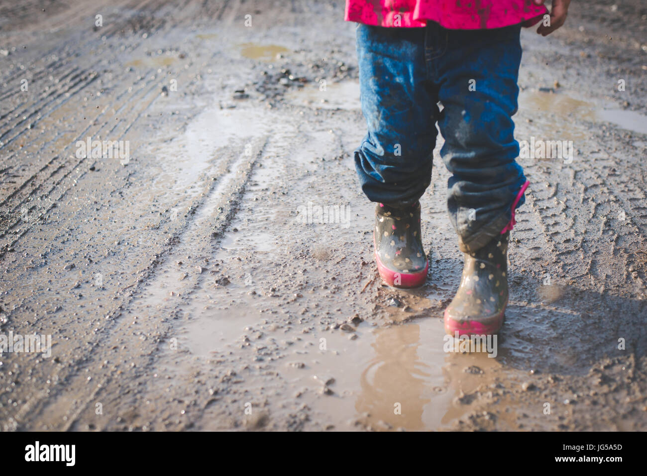 Un niño camina en el barro a lo largo de una carretera rural en Pensilvania. Foto de stock