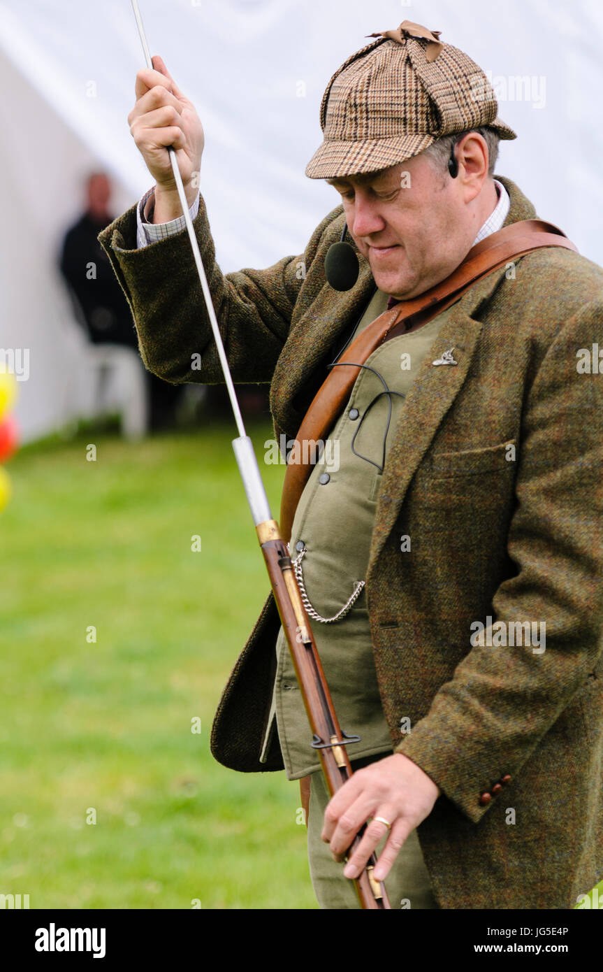 Un hombre vestido de verde irlandés chaqueta tweed deerstalker Lovat,  sombrero, chaleco y pantalón, utiliza una varilla al pack guata en su rifle  flintlock después lo Fotografía de stock - Alamy