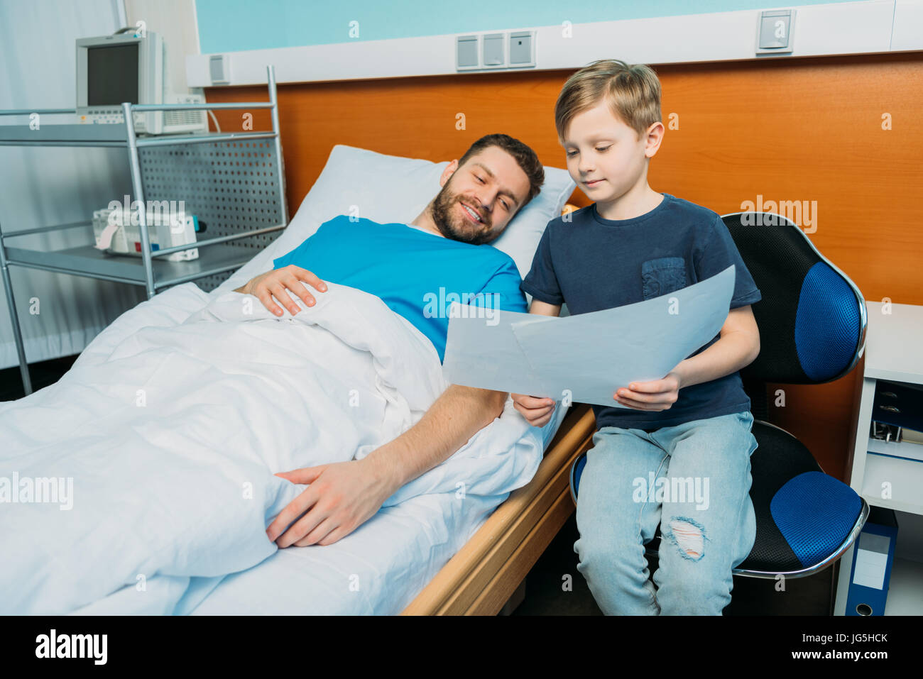 chupar Adquisición Canal Pequeño hijo mostrando padre enfermo sus dibujos en Ward, paciente del  hospital care Fotografía de stock - Alamy