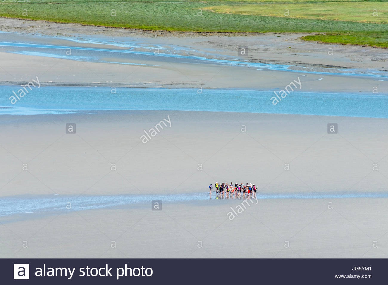 Francia, Normandía, Manche el departamento, Le Mont-Saint-Miichel. Hay turistas que caminan en las marismas cerca del Mont en marea baja. Foto de stock