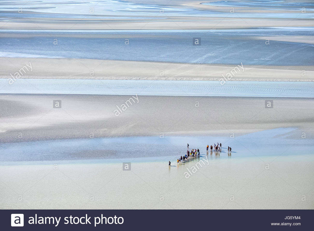 Francia, Normandía, Manche el departamento, Le Mont-Saint-Miichel. Hay turistas que caminan en las marismas cerca del Mont en marea baja. Foto de stock