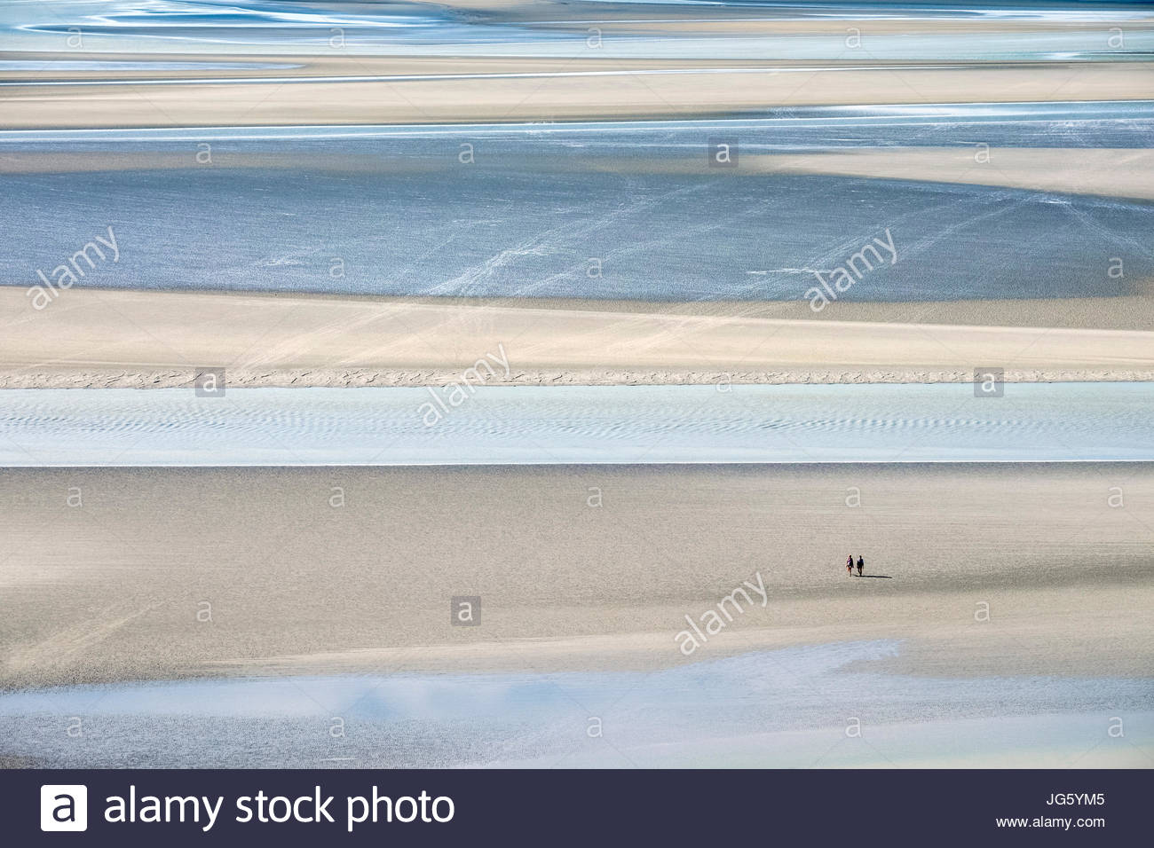Francia, Normandía, Manche el departamento, Le Mont-Saint-Miichel. Hay turistas que caminan en las marismas cerca del Mont en marea baja. Foto de stock