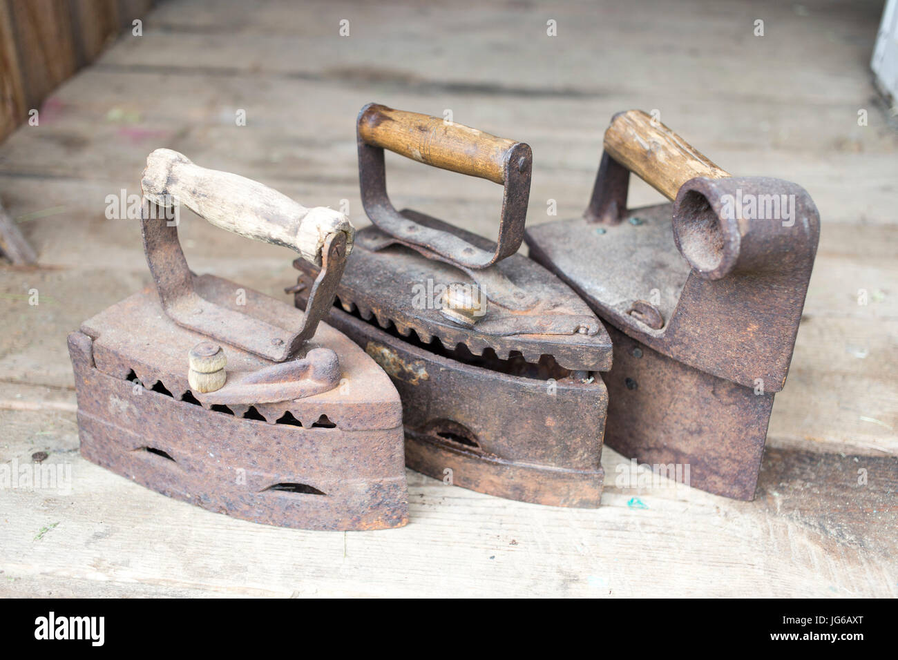 Vintage planchas. El trabajo de hierro sobre las brasas. Tres modelos de planchas  antiguas en un fondo de madera Fotografía de stock - Alamy