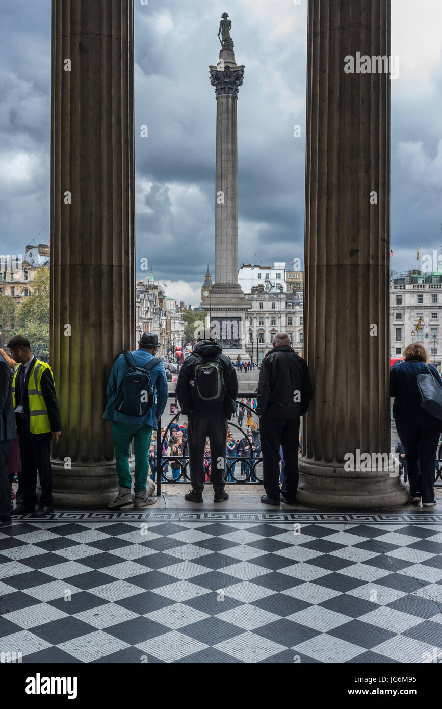 Los turistas mirando hacia Trafalgar Square desde el balcón de la National Gallery Foto de stock