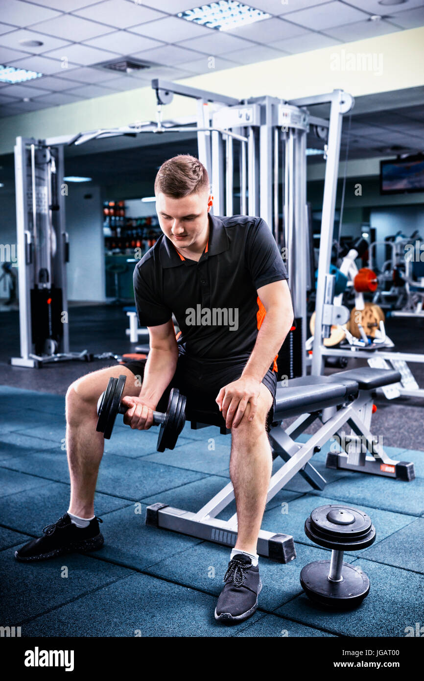 Los jóvenes deportistas en ropa deportiva hombre levantar pesos y sus bíceps en un gimnasio Fotografía de stock - Alamy