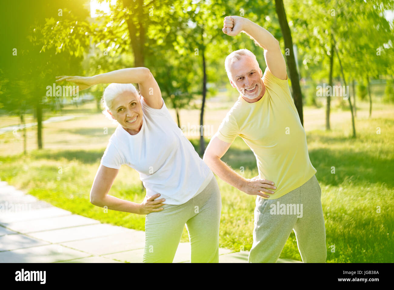Alegre, sonriente anciano pareja realizando ejercicios deportivos Foto de stock