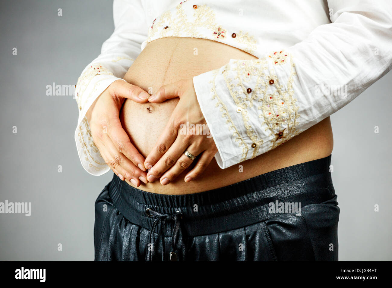 Mujer embarazada la creación de forma de corazón con su mano sobre el vientre. Foto de stock
