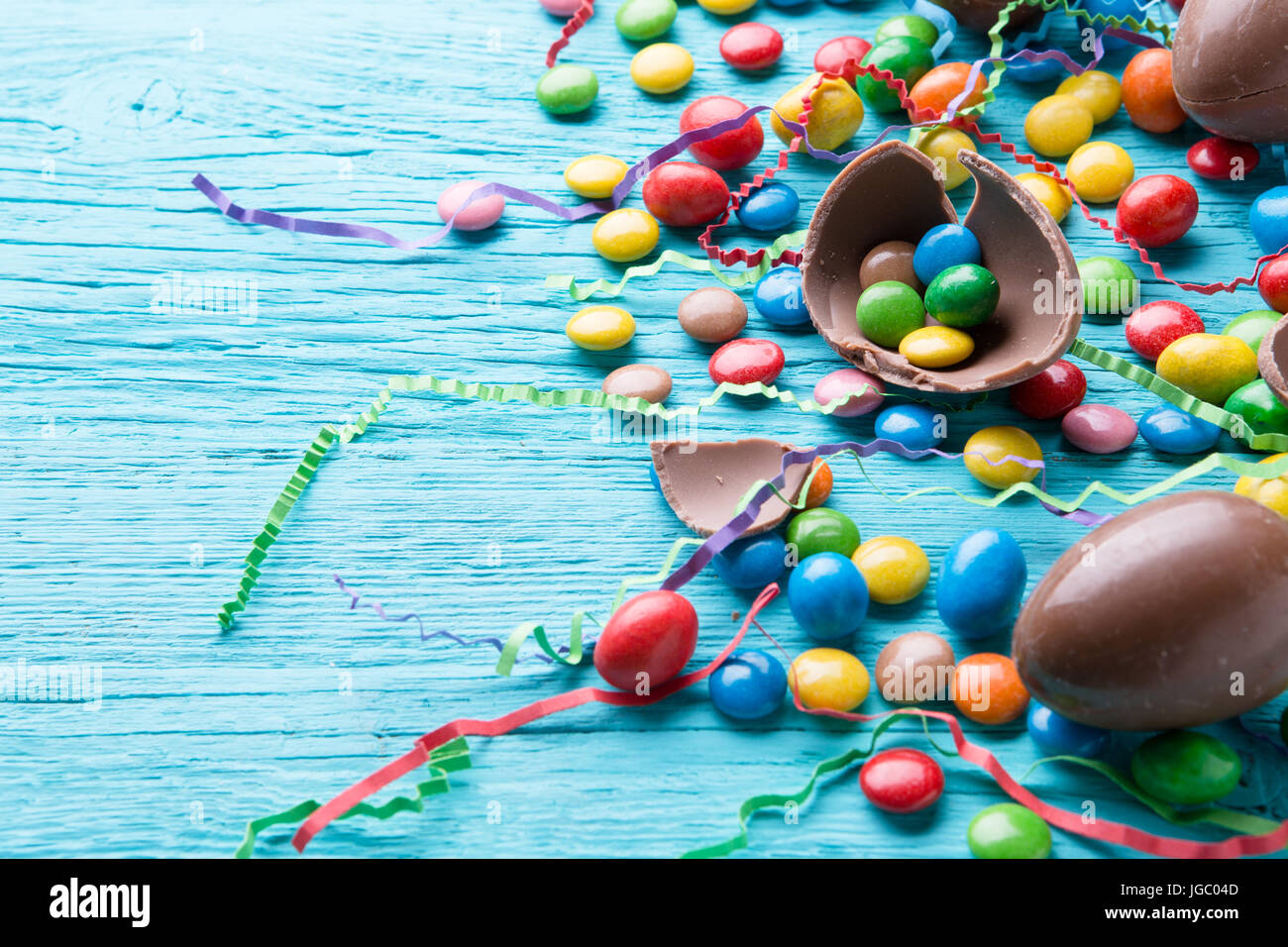 Multicolor Jelly Beans, huevos de chocolate, la cinta sobre la mesa de madera azul Foto de stock