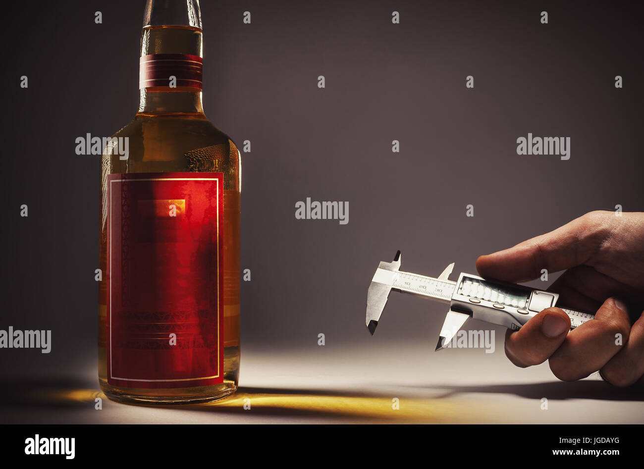 Beber alcohol en una botella y la mano con micro herramienta Medición. Foto de stock