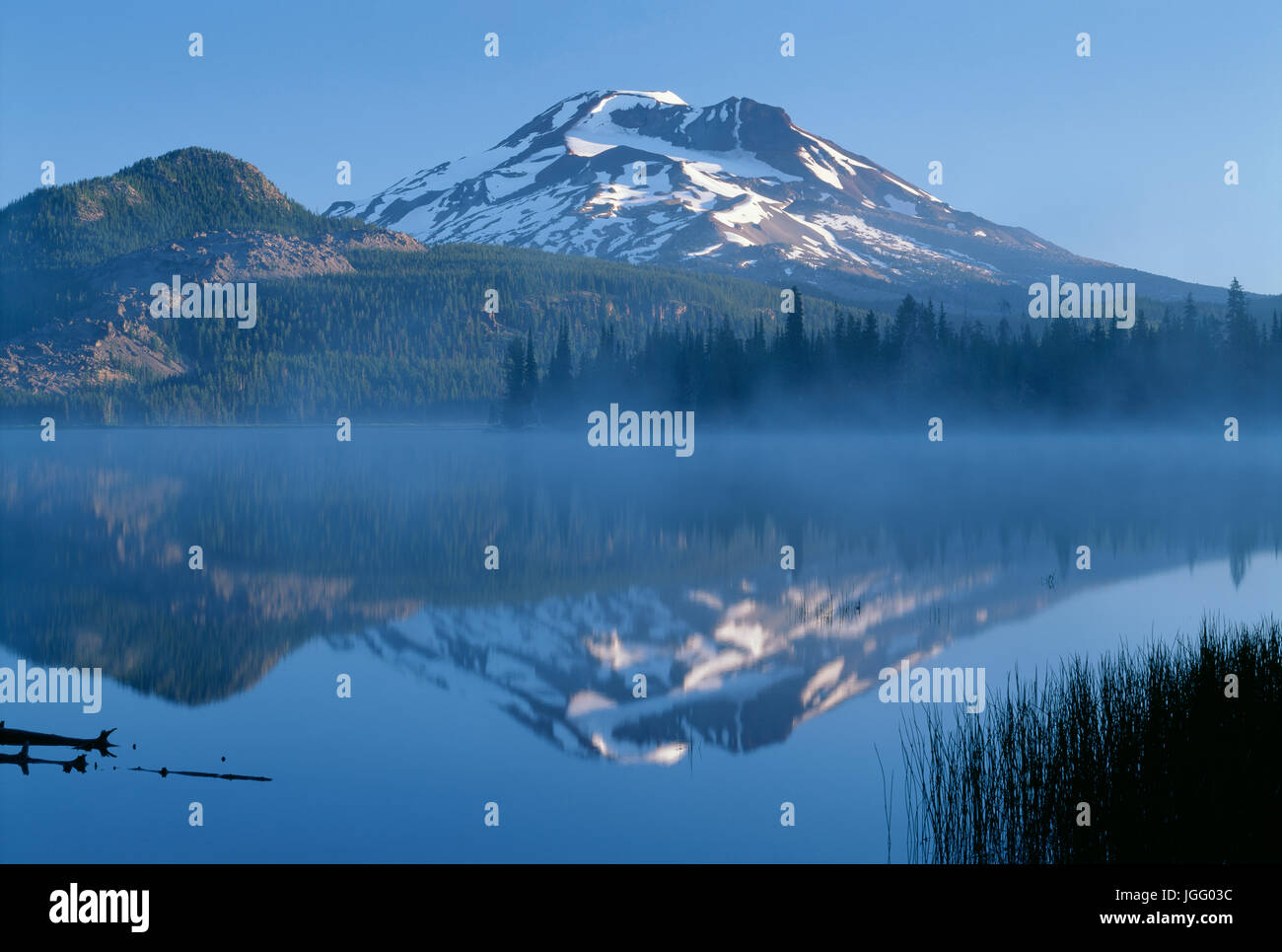 USA, Oregon, Deschutes National Forest, Hermana Sur se refleja en las brumosas aguas del lago chispas en las primeras horas de la mañana. Foto de stock
