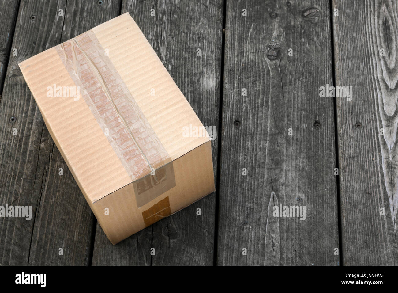 Entrega de cartón paquete entregado a puerta sobre fondo de madera vieja Foto de stock