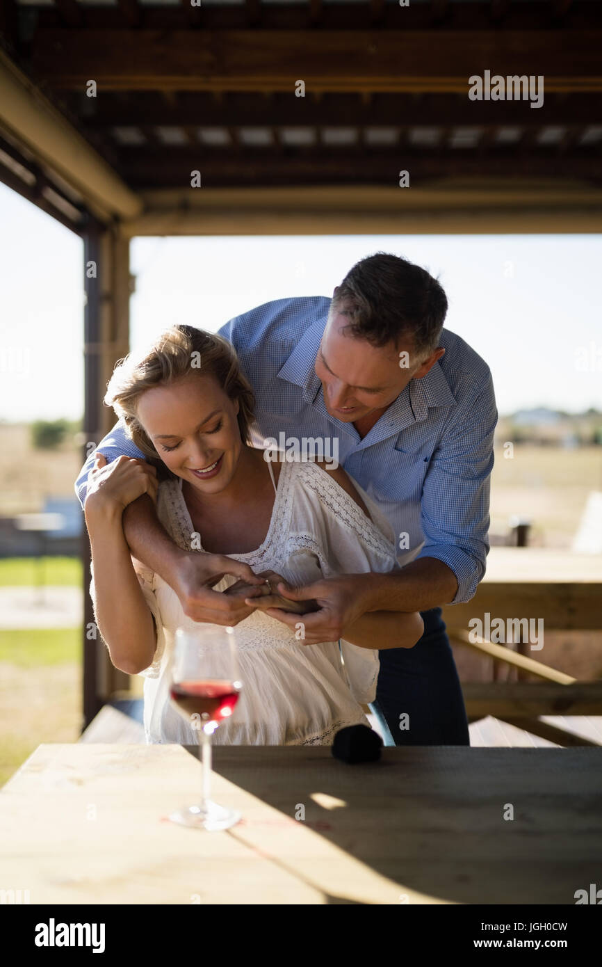 Hombre sonriente luciendo anillo de compromiso a mujer en restaurante. Foto de stock