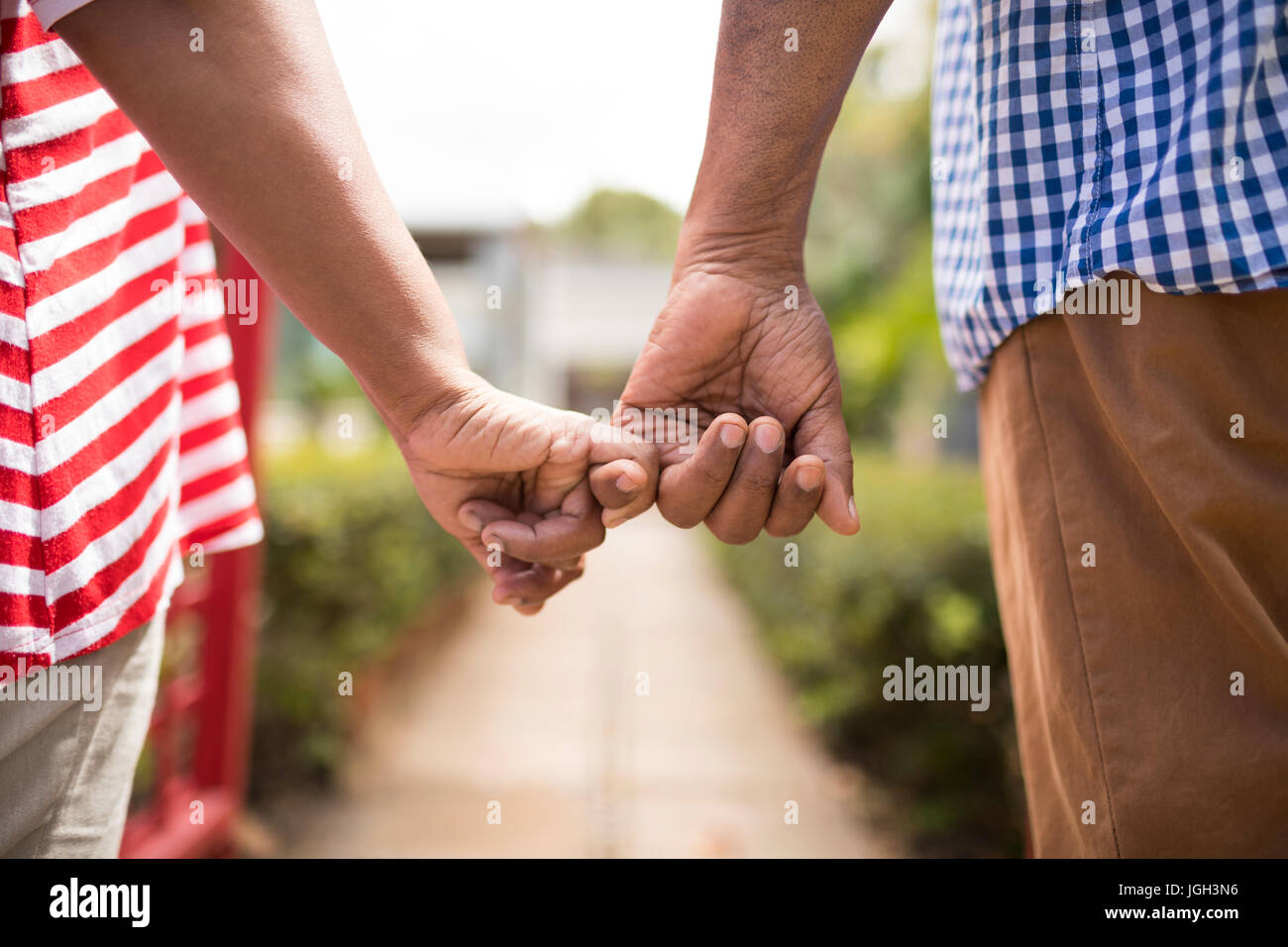 Imagen recortada de alto par la celebración de dedos pequeños mientras está de pie en el patio Foto de stock