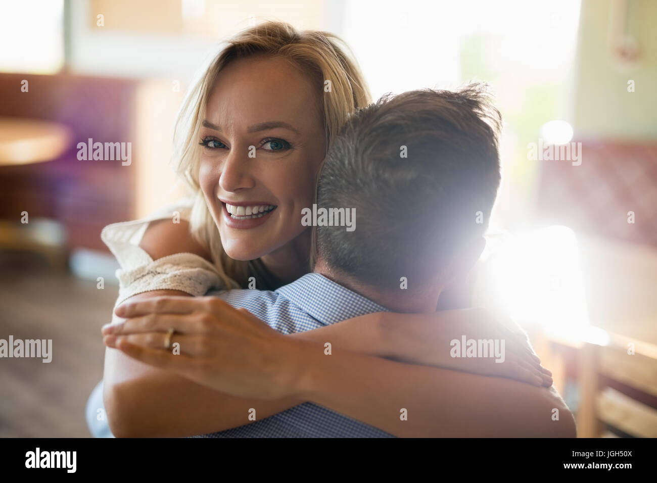 Sonriente pareja abrazándose entre otros en restaurante. Foto de stock