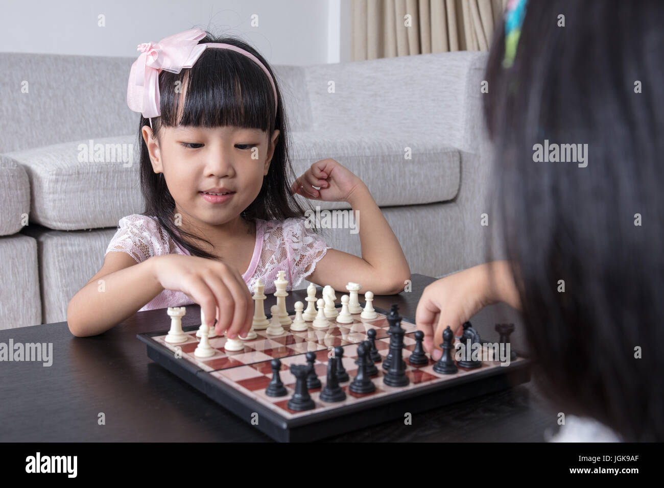 Chino Asia hermanitas jugando ajedrez juntos en el salón de casa. Foto de stock
