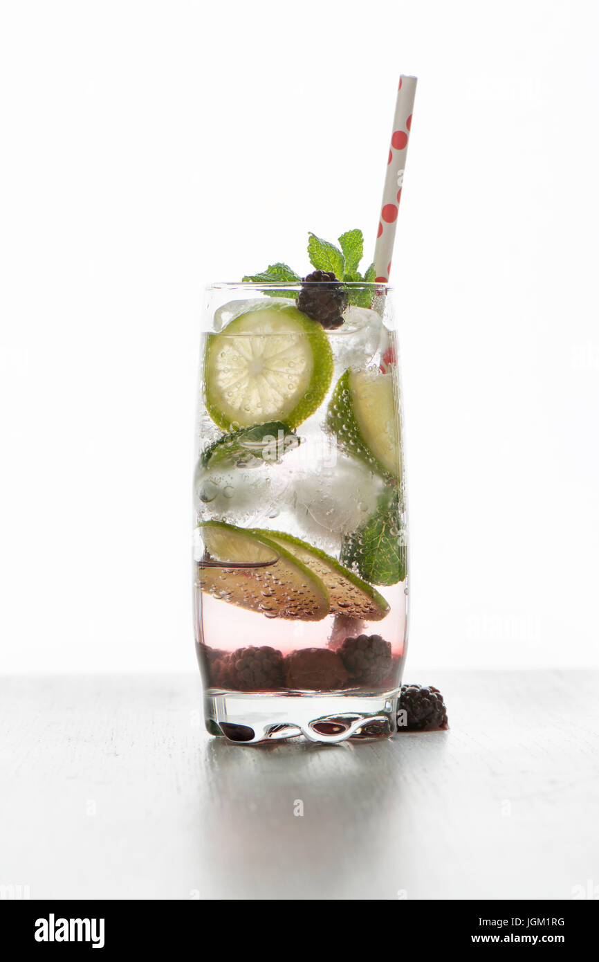 Gin Tonic cóctel con hielo, limón y frutos rojos, fondo blanco