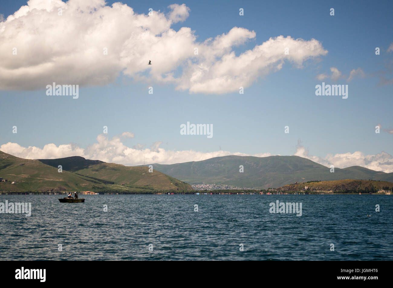 Barco de pesca en el Lago Sevan en Armenia con nubes y montañas. Foto de stock