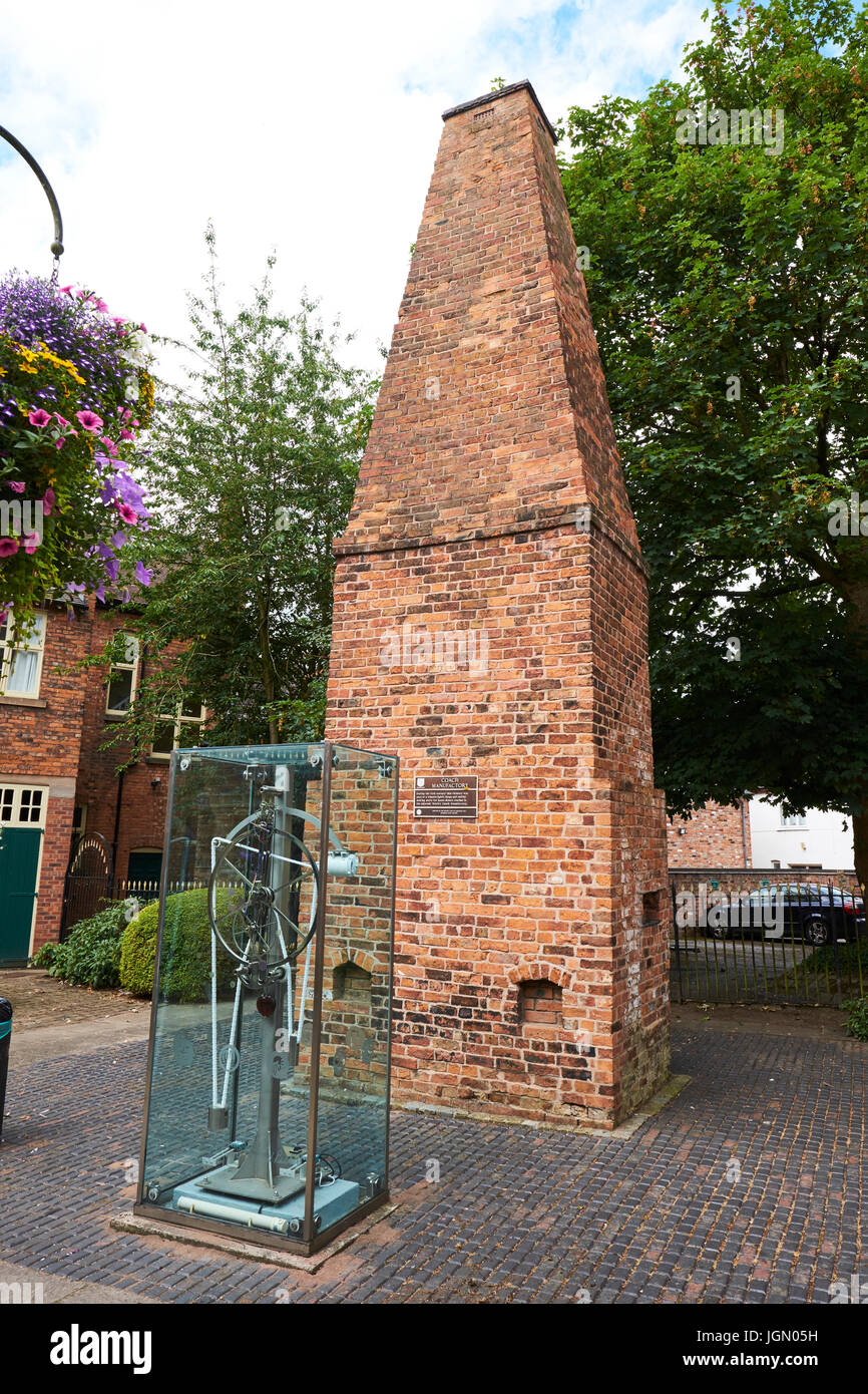Milenio reloj hecho colocado delante de la chimenea que formaba parte de un Wheelwright la forja y herrería, Patio de cacao, Nantwich, Cheshire, Reino Unido Foto de stock