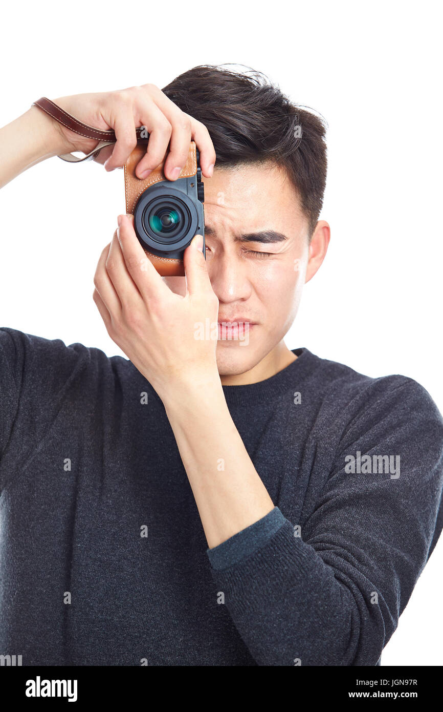 Joven hombre asiático tomando una foto con la cámara, aislado sobre fondo blanco. Foto de stock