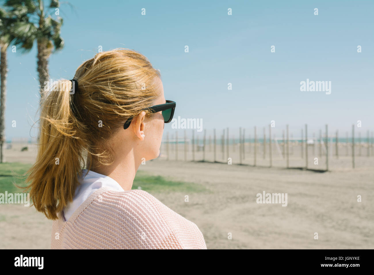 Chica rubia en gafas de sol mirando el mar, el día de viento cerca de la  playa Fotografía de stock - Alamy