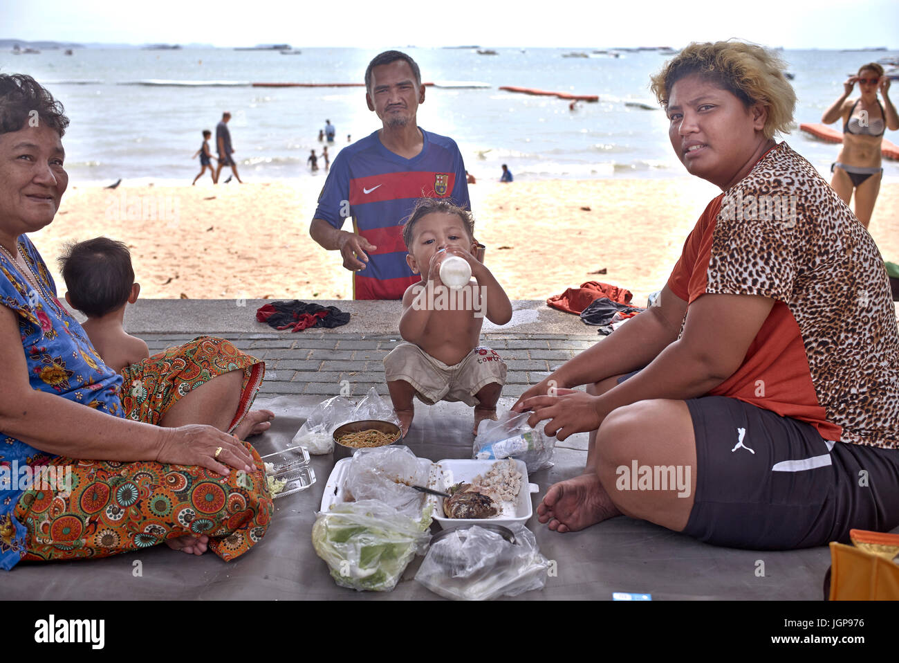 Tailandia comprende tres generaciones de la familia de la madre, abuelos y niños comiendo fuera en la playa. Sudeste de Asia Pattaya Foto de stock