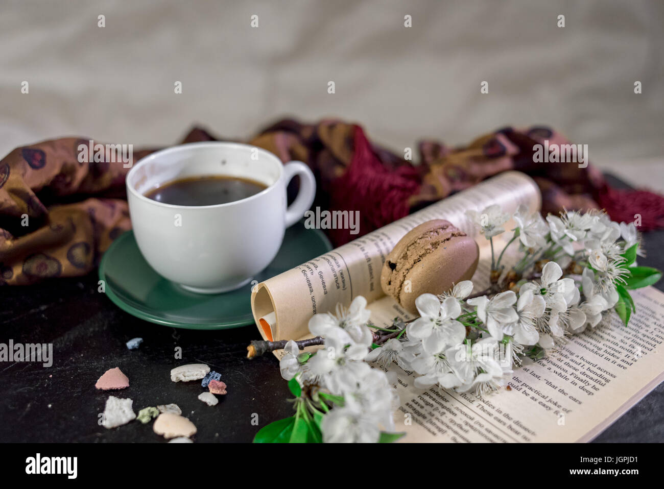 Leer un libro con una taza de café o té caliente y bufanda y la rama de  cerezo en flor Fotografía de stock - Alamy