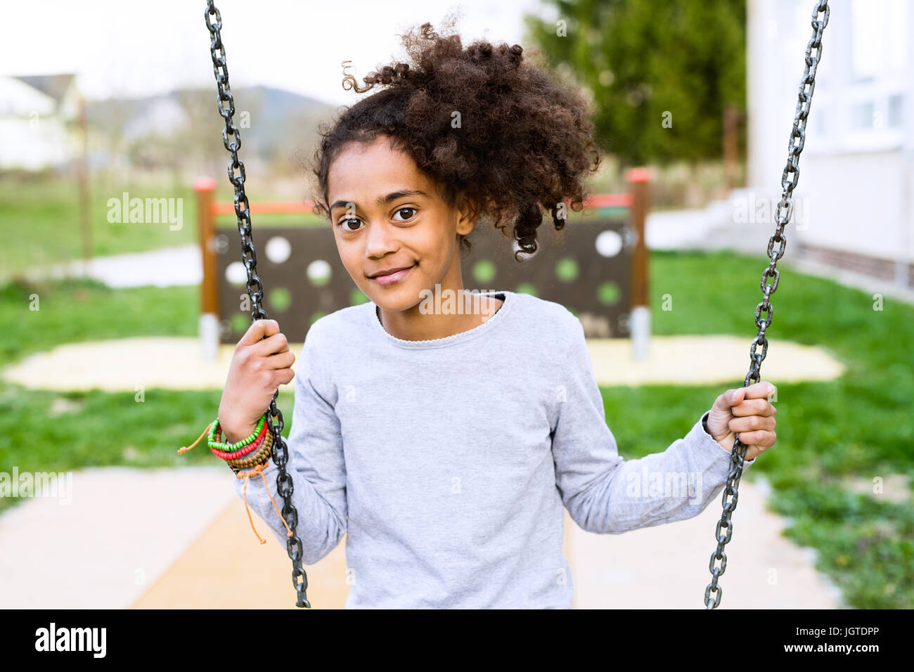 African American Girl afuera sentado en swing. Foto de stock