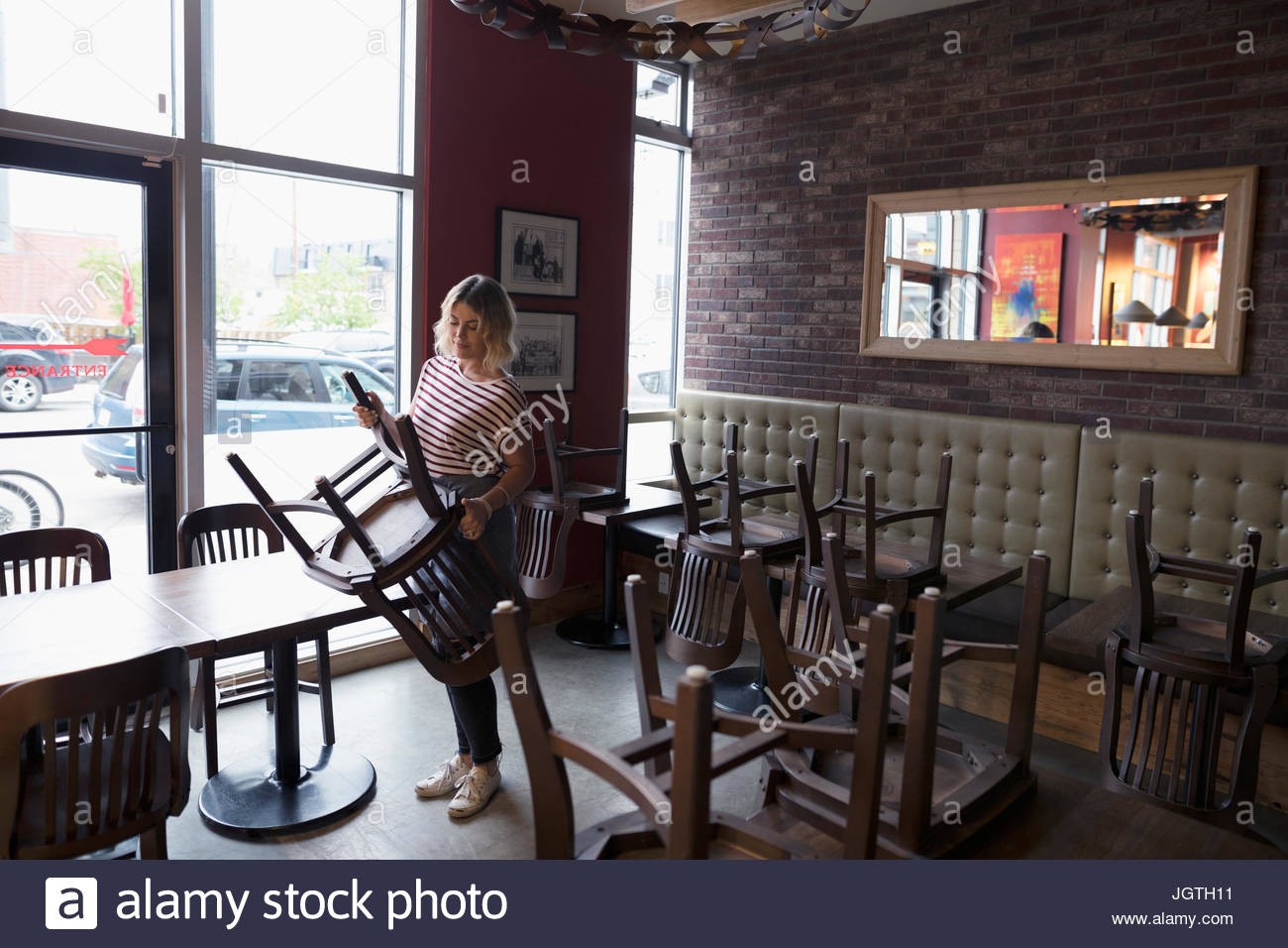 Camarera pasando sillas sobre las mesas, en la cena de clausura Foto de stock