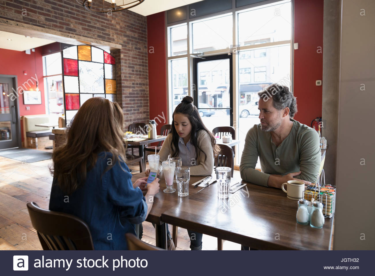 Los padres con su hija adolescente en la mesa de comedor comedor Foto de stock