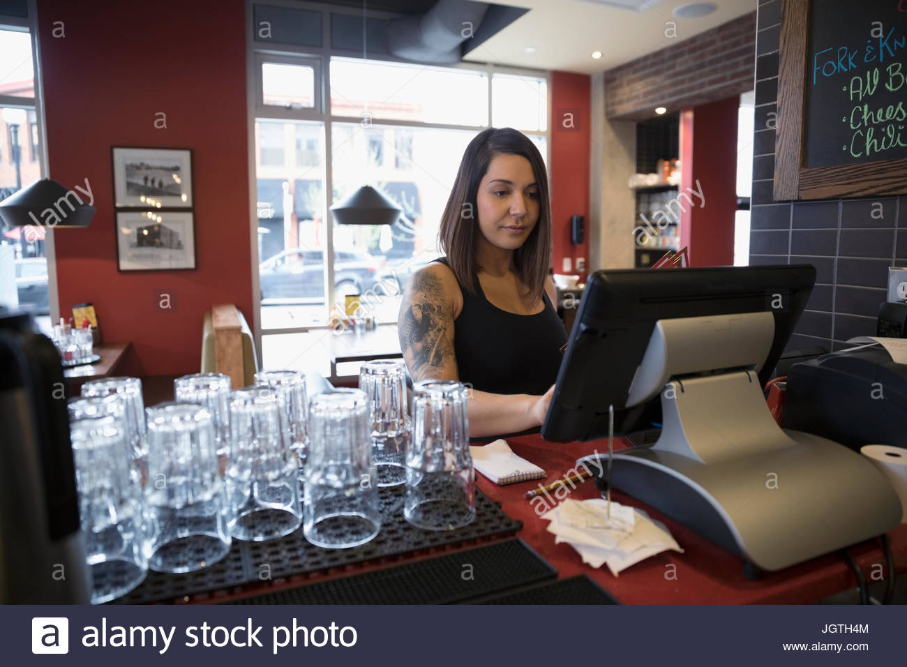Camarera tatuados utilizando el ordenador, introducir orden en el restaurante Foto de stock