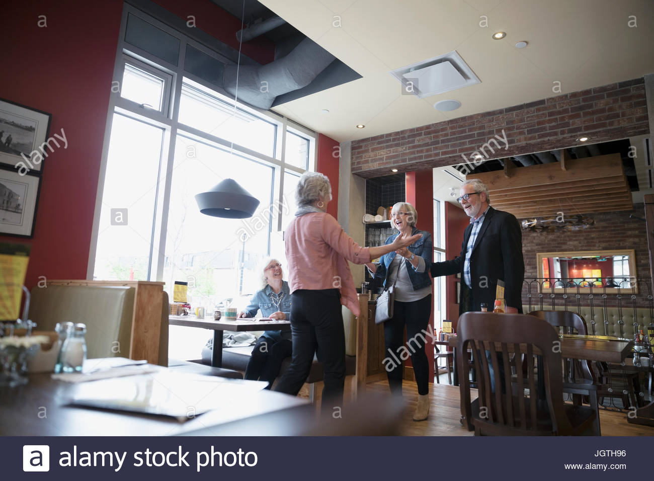 Entusiasta mujer senior saludo amigos en diner booth Foto de stock