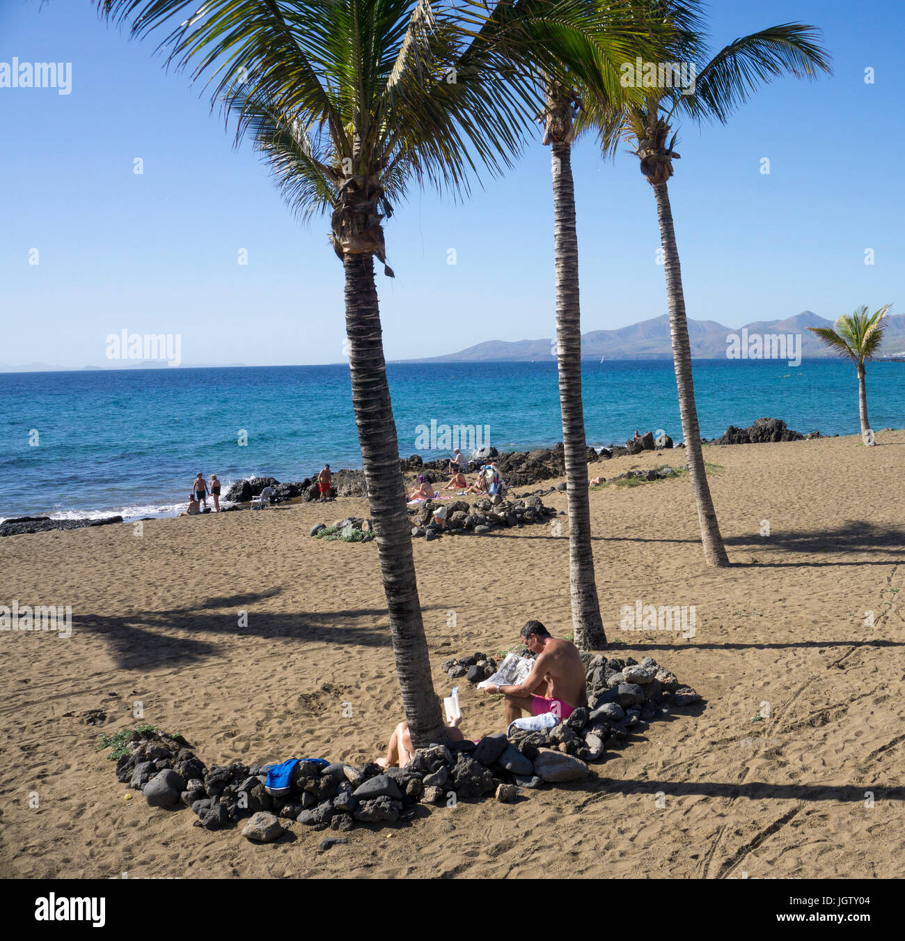 Badegaeste zwischen kleinen schutzmauern windschutz lavasteinen (AUS), playa grande, grosser badestrand en Puerto del Carmen, Lanzarote, kanarische en Foto de stock