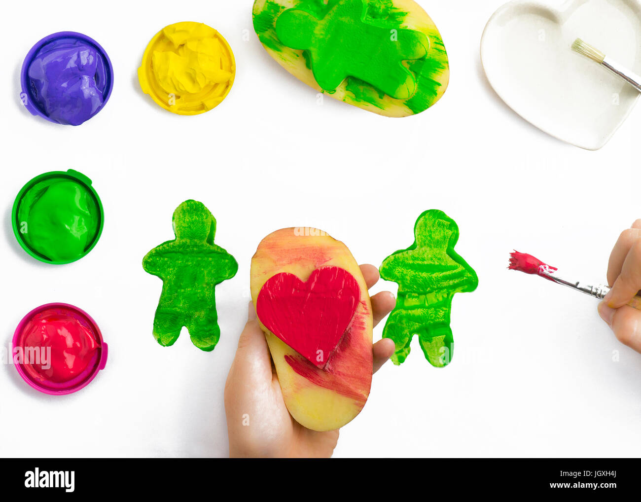 Childs, jugar a mano pintura con sellos de papa, cepillado en forma de  corazón rojo, verde, amarillo, púrpura y poster pinturas algunos objetos  aislados en un WH Fotografía de stock - Alamy