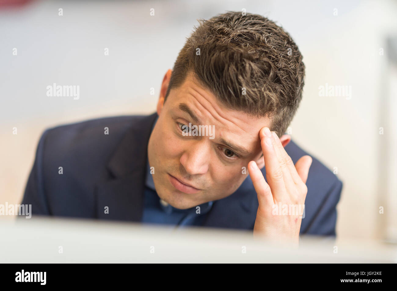 Preocupado empresario mirando su equipo en Office Foto de stock