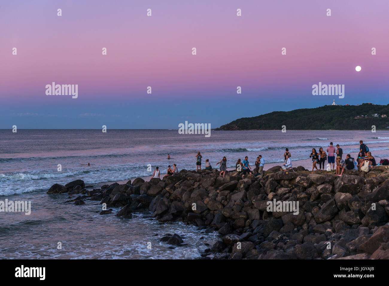 La gente disfruta de la puesta de sol y de la luna llena lugar en Byron Bay, New South Wales, Australia. Foto de stock