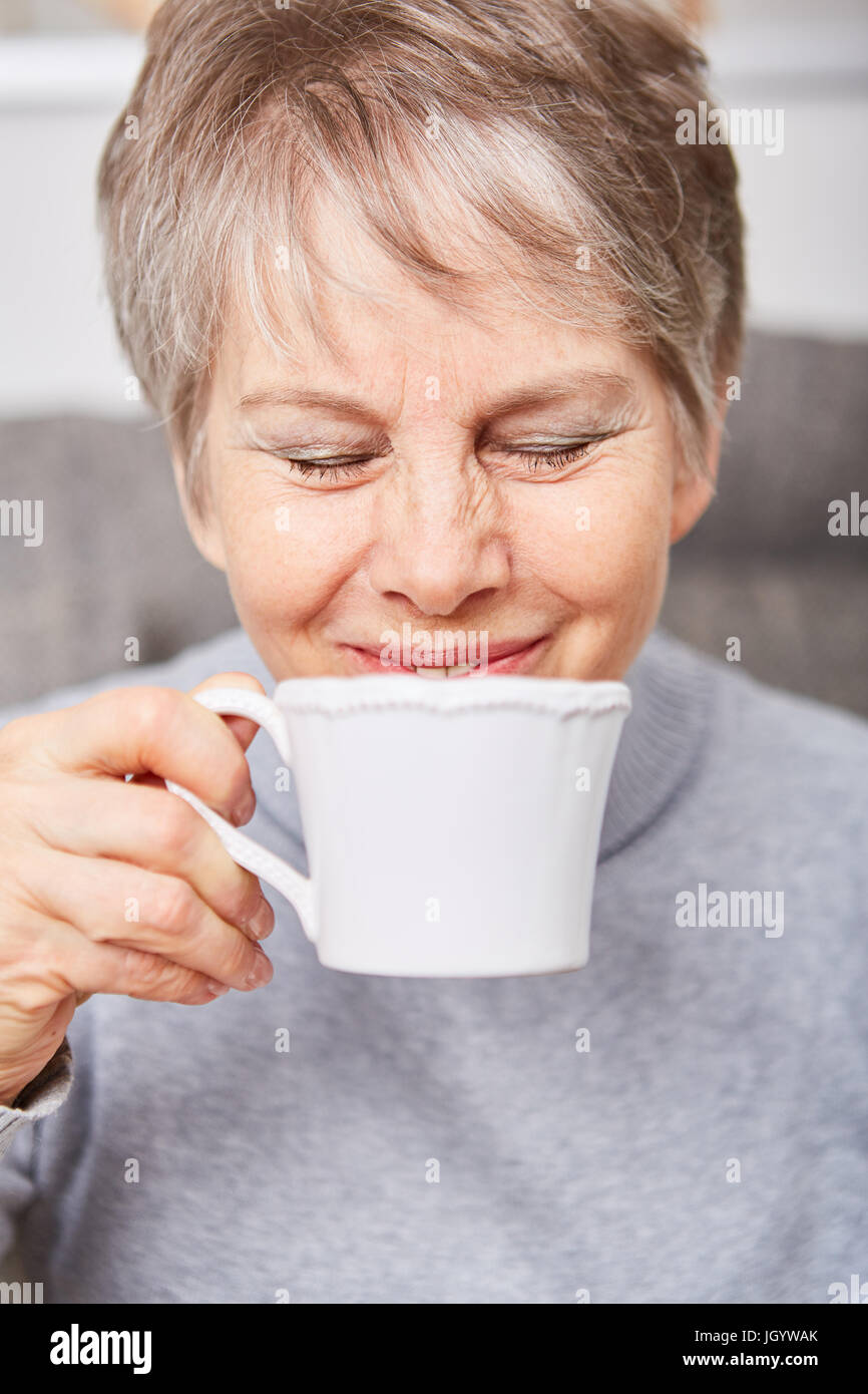 Feliz mujer con taza de café bebidas con goce Foto de stock