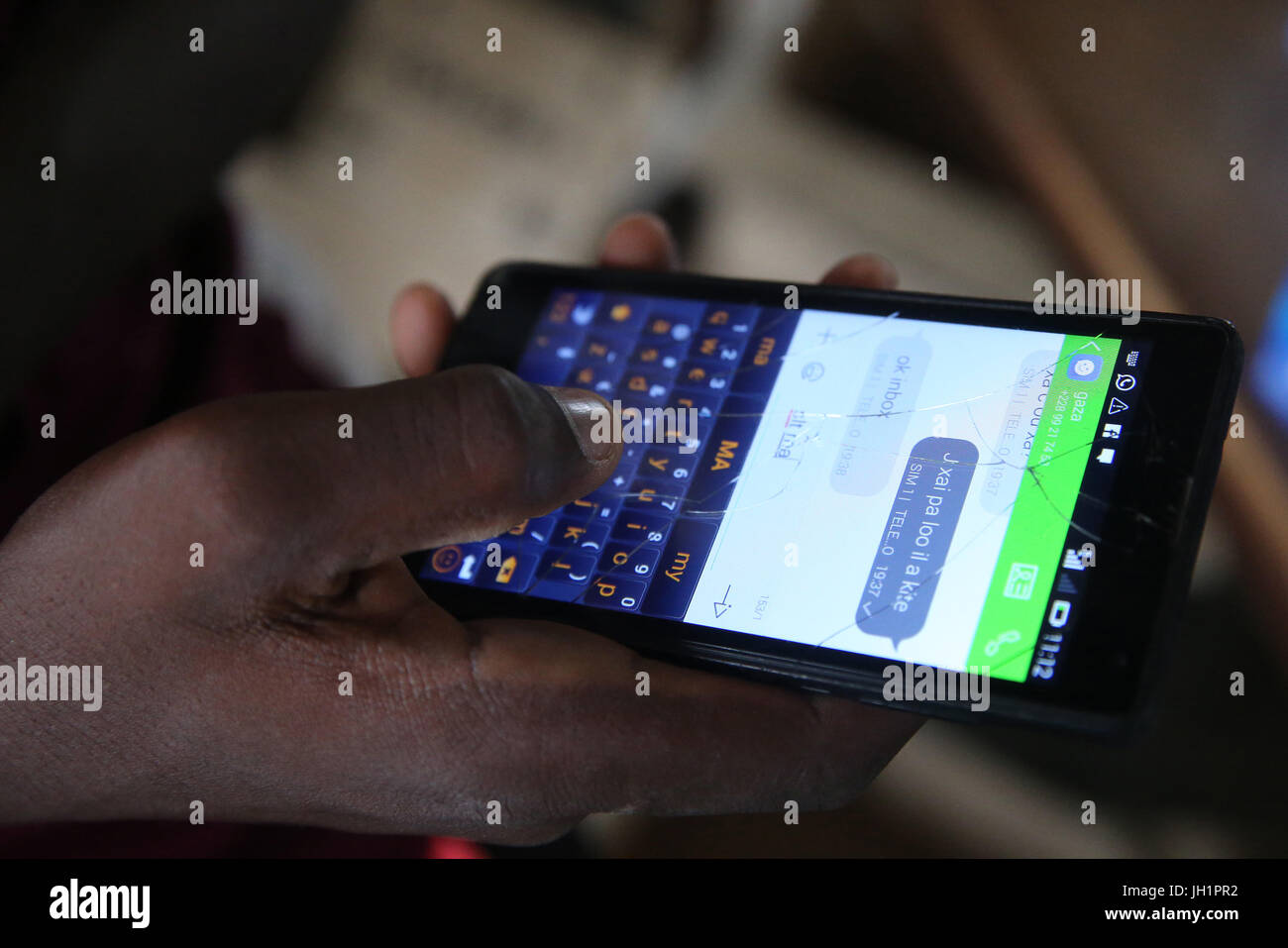 Cerca de un hombre africano usando un teléfono inteligente con una pantalla rajada. Lome. Togo. Foto de stock