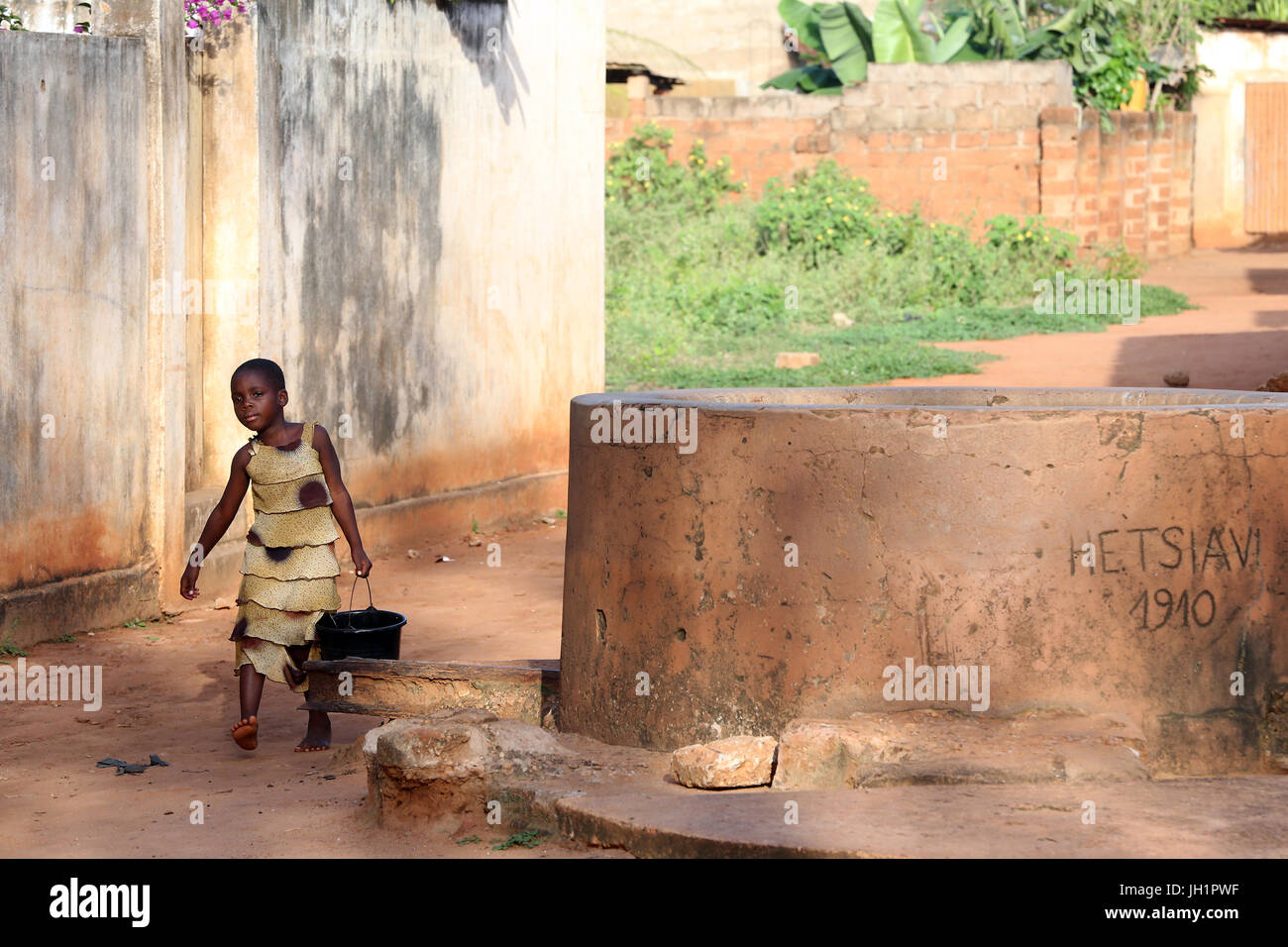 La vida del pueblo africano. Chica con agua cerca de un pozo. Togoville. Togo. Foto de stock