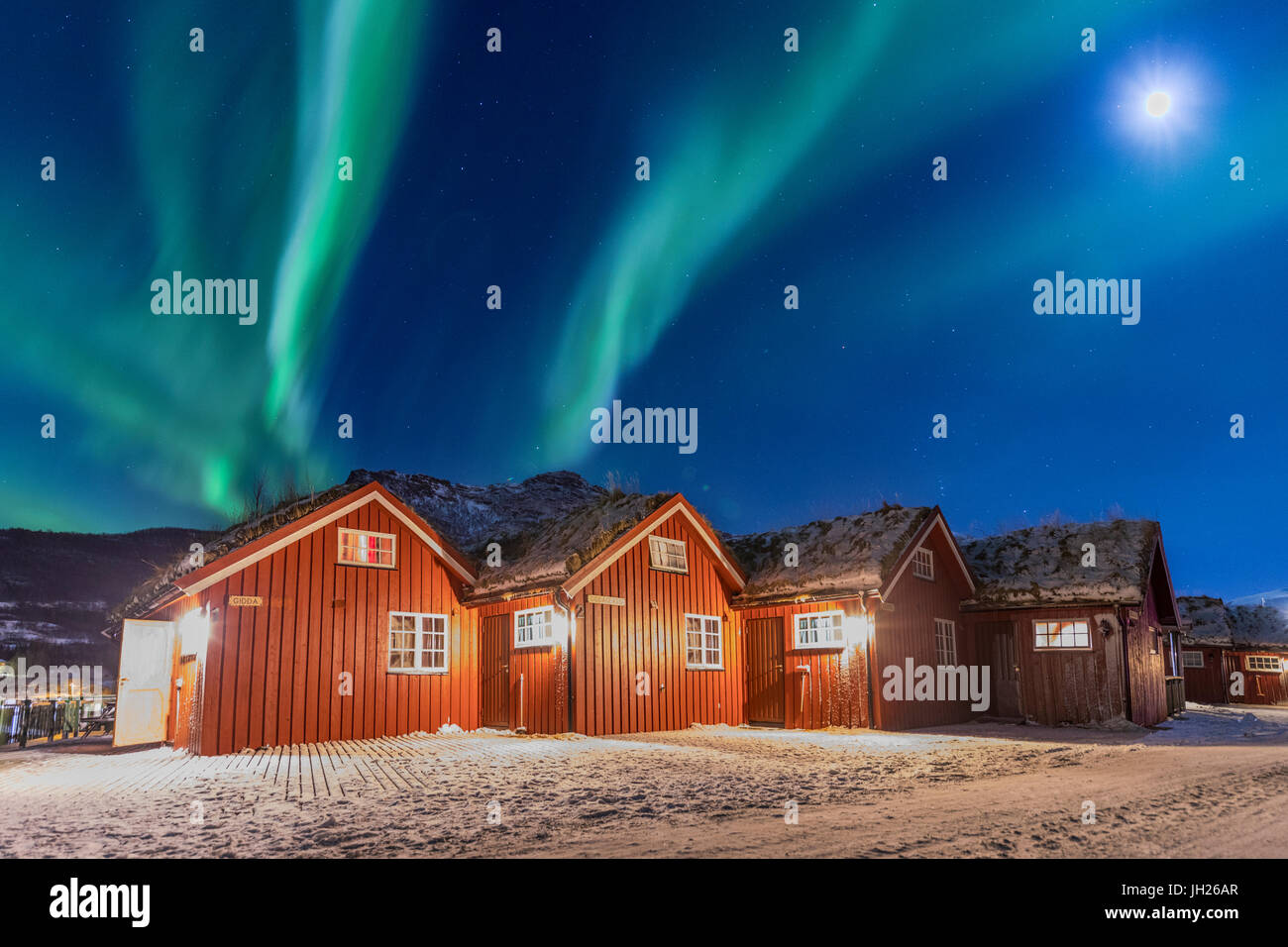 Las luces del norte y la luz de la luna hasta cabañas de madera típicos llamados Rorbu, Manndalen, Kafjord, Lyngen Alpes, Troms, Noruega Foto de stock