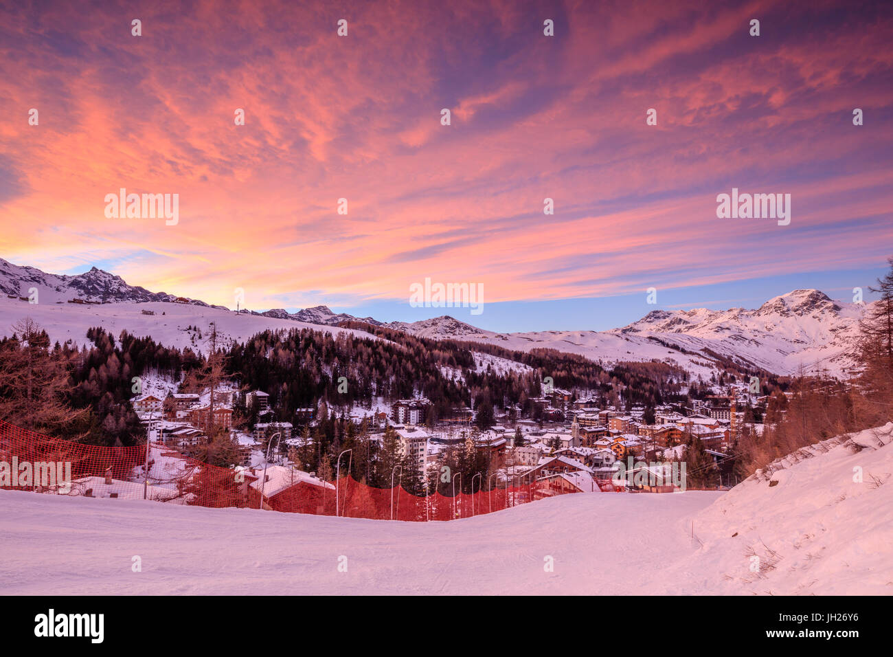 Nubes rosadas al atardecer en la aldea alpina de Madesimo y las nevadas pistas de esquí, Valle Spluga, Valtellina, Lombardía, Italia Foto de stock