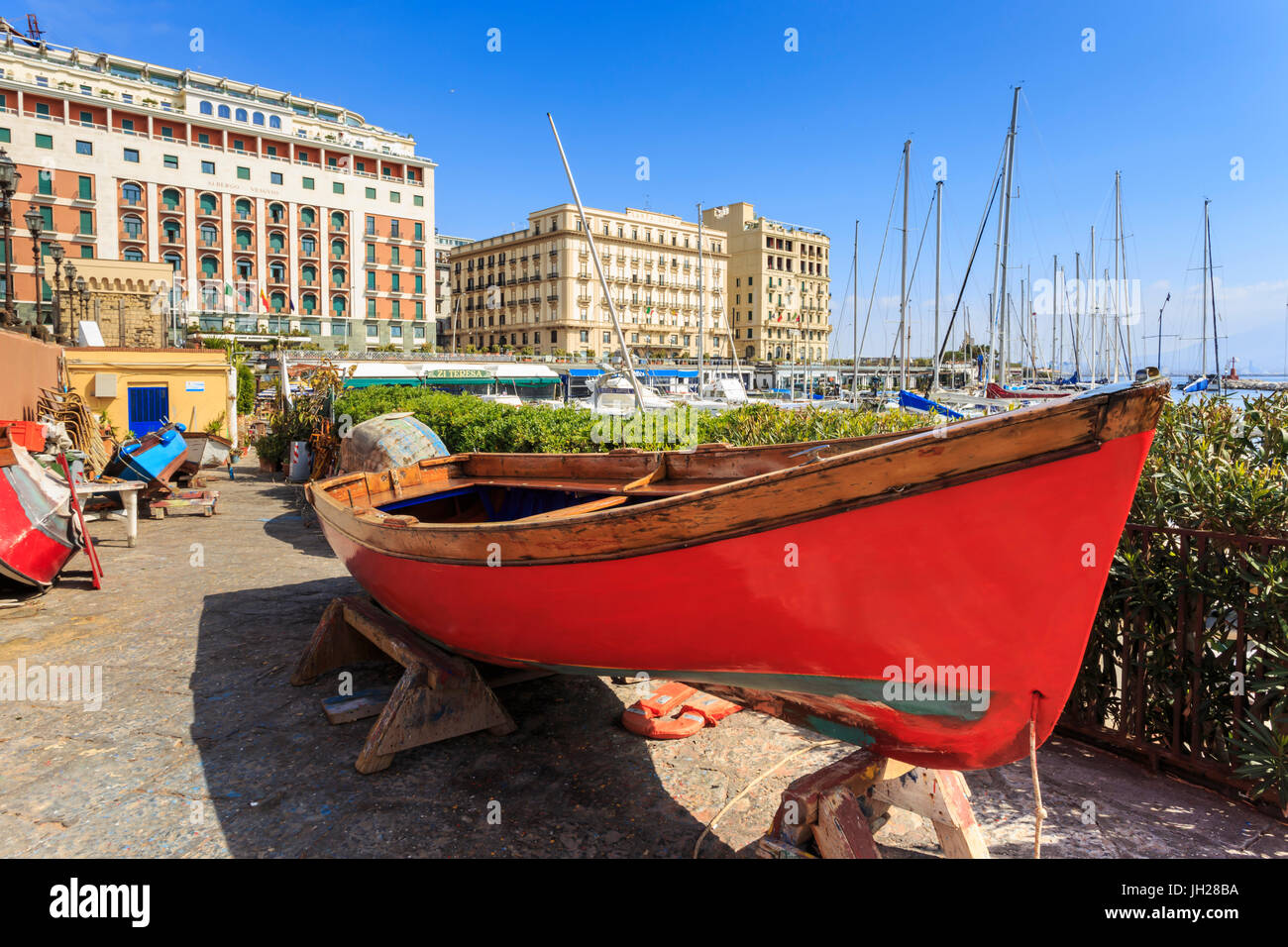 Coloridos botes a remo en reparación en el marina Borgo Marinaro, con el telón de fondo de grandes hoteles, Chiaia, Ciudad de Nápoles, Italia Foto de stock