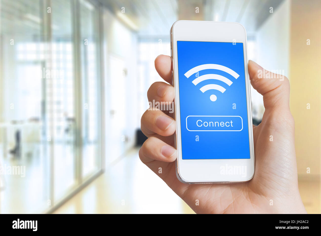 Mano sujetando un smartphone con un botón para conectarse a una conexión a internet inalámbrica en la pantalla con el icono de wifi Foto de stock