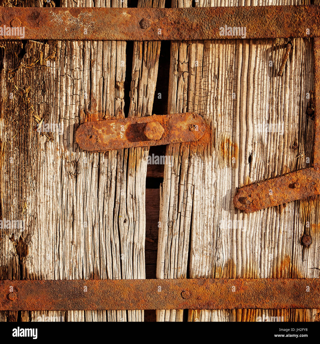 Puerta de madera antigua con elementos oxidados. Foto de stock