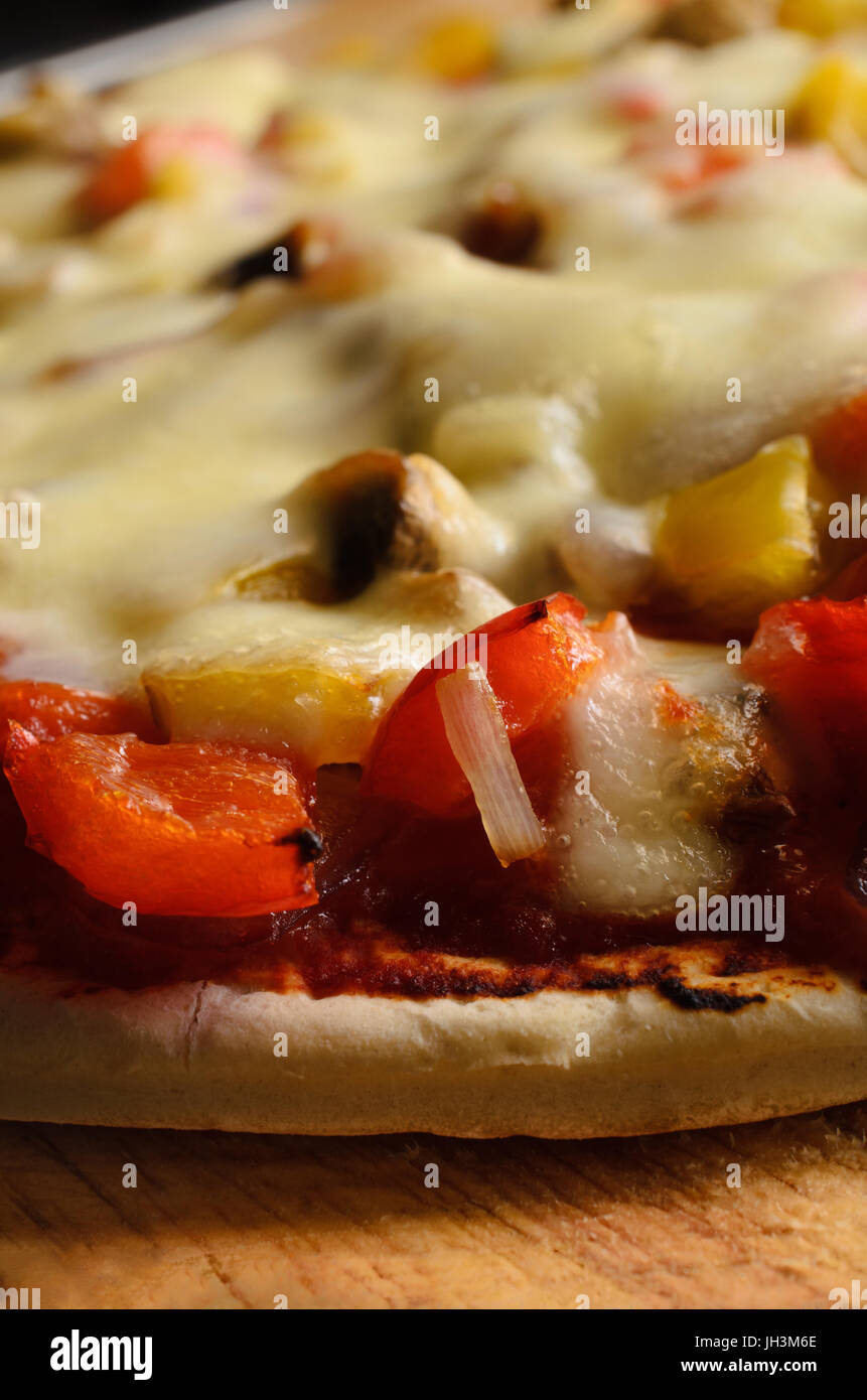 Muy de cerca (macro) de una pizza vegetariana cocido con pimientos rojos y amarillos, cebollas, setas y queso mozzarella. Foto de stock